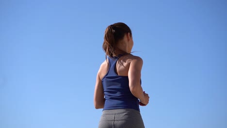 Back-view-of-sporty-girl-jogging-at-sunny-day